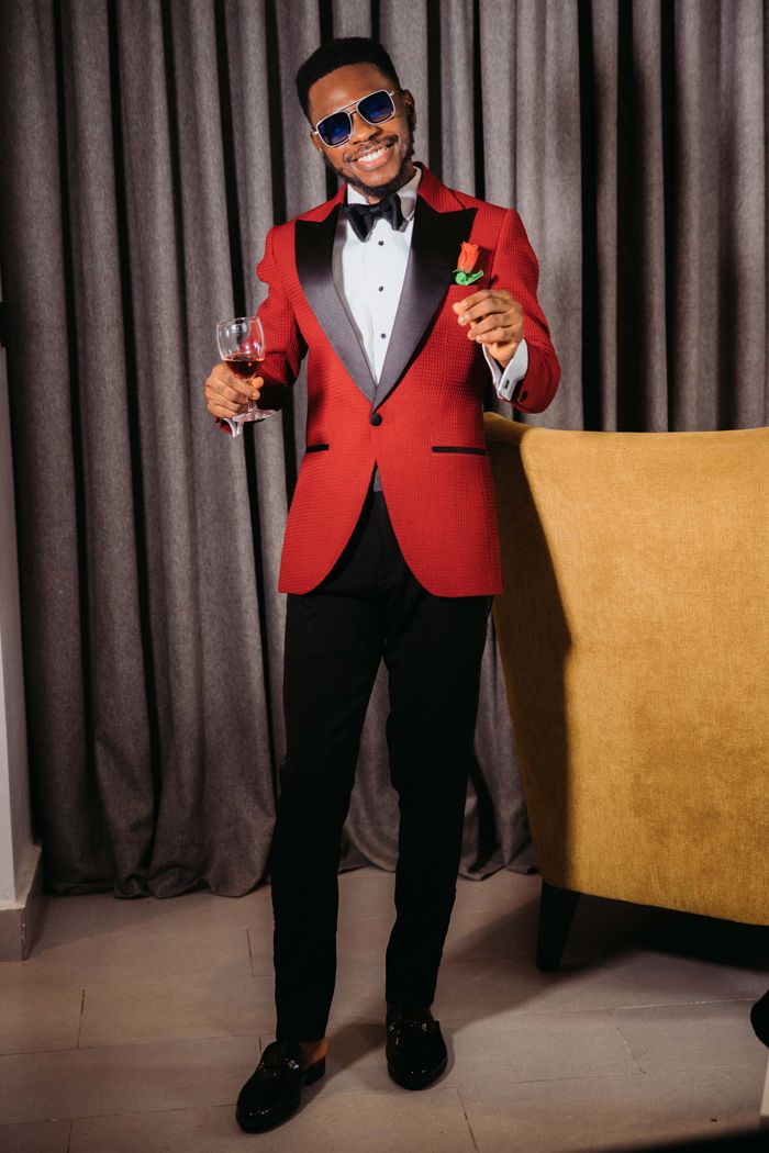 The Art of Drawing Readers In: Your attractive post title goes here Elegant man smiling in a red tuxedo with sunglasses, holding a wine glass indoors.