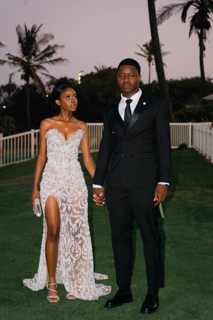A stylish couple poses elegantly in formal wear at sunset, capturing sophistication and grace.